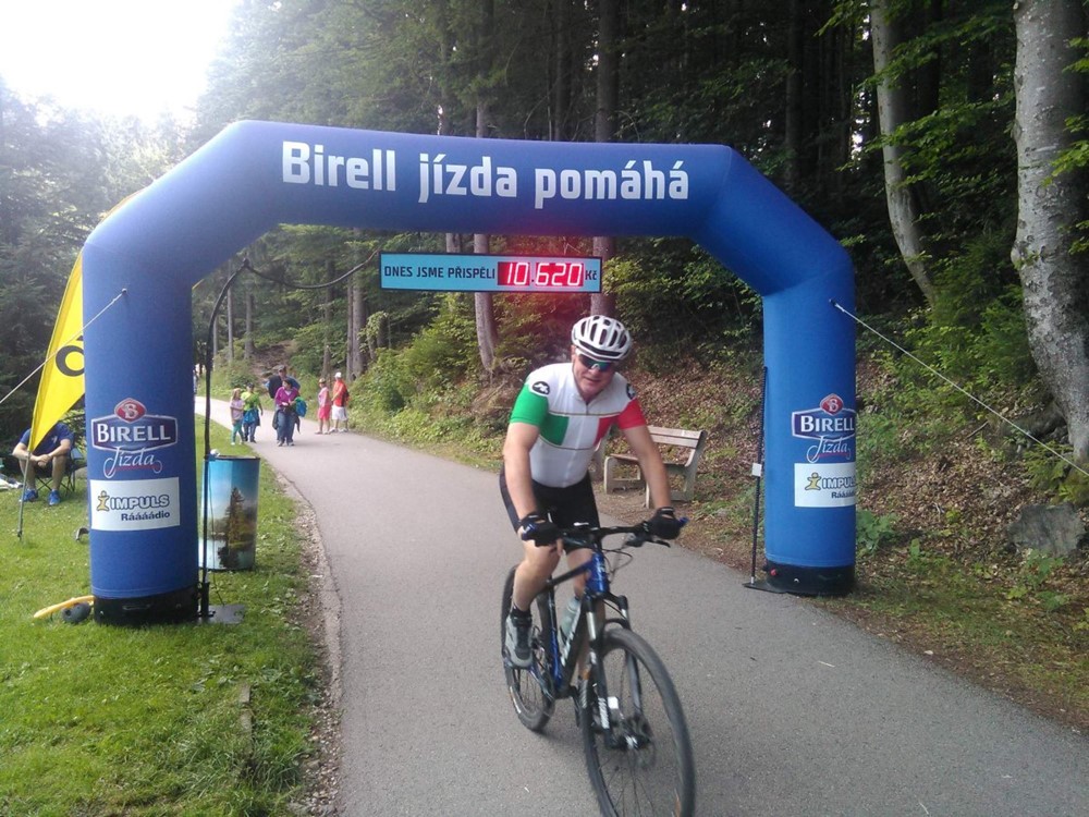 Cyklista projíždí Birell bránou ve Špindlerově Mlýně a pomáhá handicapovaným získat handbiky a kola.